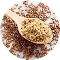 Wooden spoon filled with flaxseed meal surrounded by whole flaxseeds on a light background