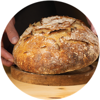 Loaf of bread in a wooden bowl held by a hand