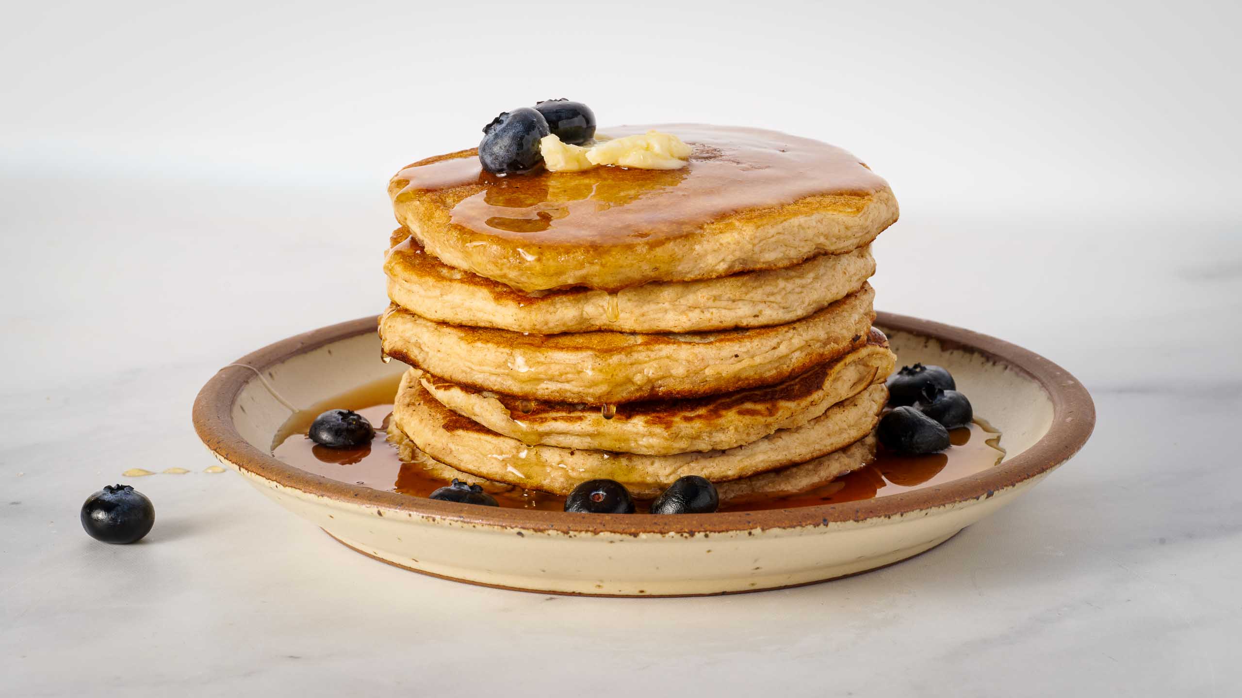 Stack of pancakes with syrup and blueberries on a plate
