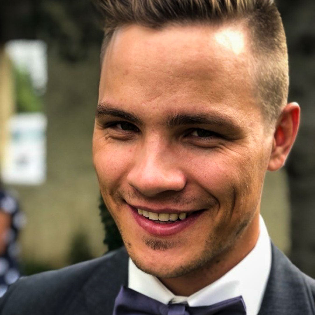 Man wearing a suit and bow tie with a blurred background (Justin Perault)