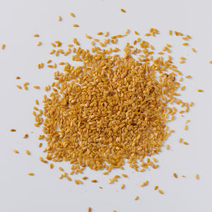 golden flax seeds scattered on a white background